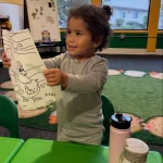 Preschooler showing completed artwork at East Bay, California preschool